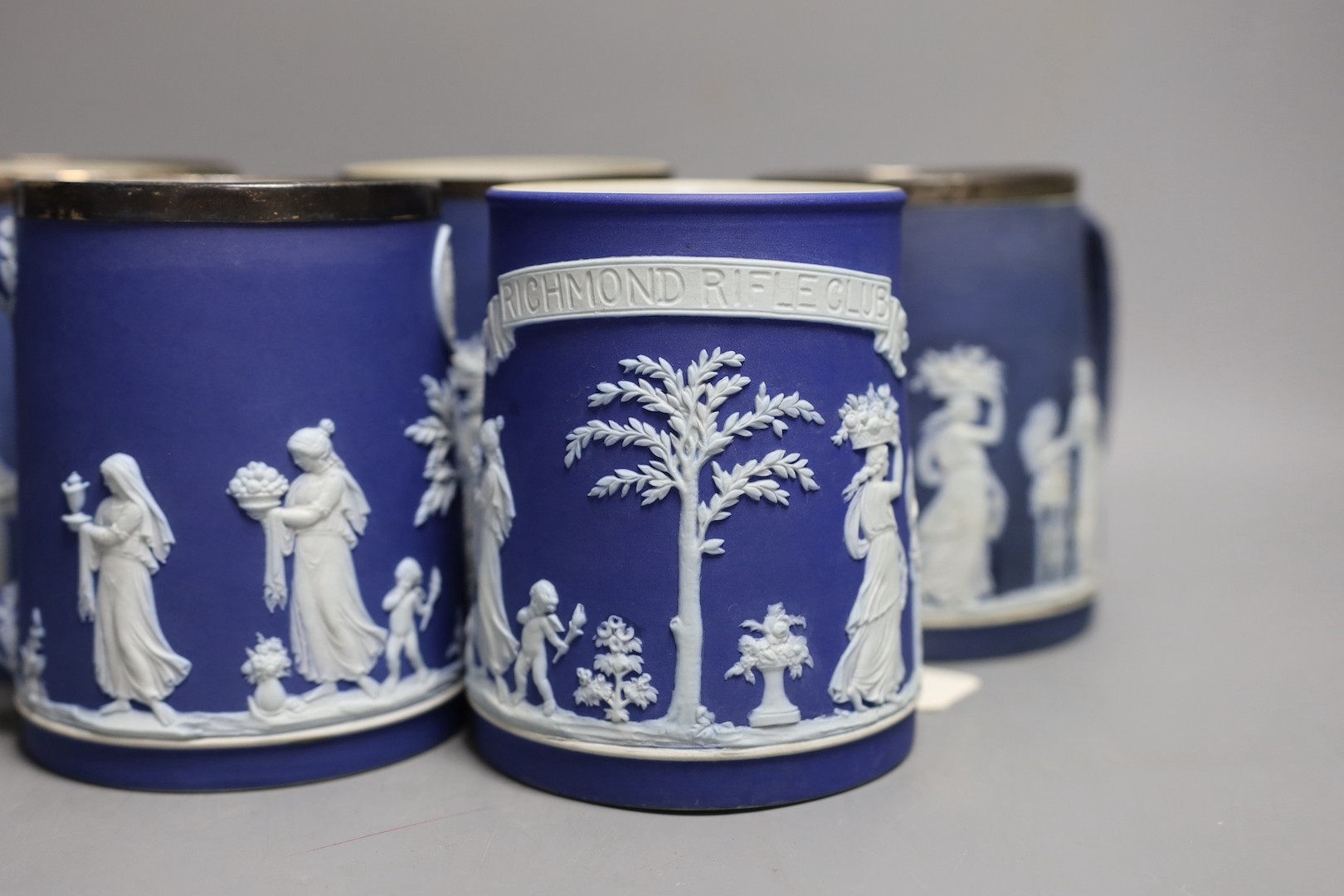 Five Wedgwood for Elkington & Co. blue jasper rifle or shooting club trophy mugs, 12.5cm high some with silver mounted rims, including Richmond rifle club, London Scottish etc.